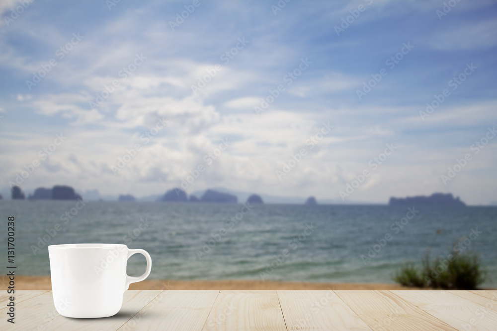 Hot coffee cup on wooden table top on blurred beach background