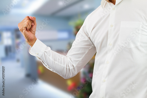 Business man wearing white shirt raising right fist up with cheerful on blurred office background