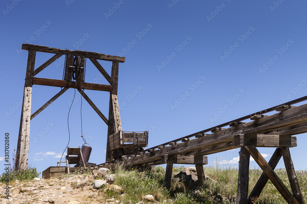 Old mining ore cart on trestle with head frame under blue sky. Old mining ore cart on trestle with head frame under blue sky.