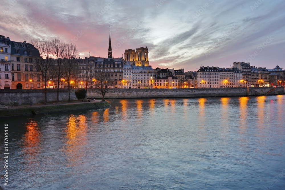 Beautiful pink sky at sunset over the Notre-Dame cathedral and the Seine River in Paris, France