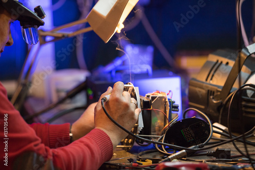 Man with safety glasses repairing motheboard with soldering iron