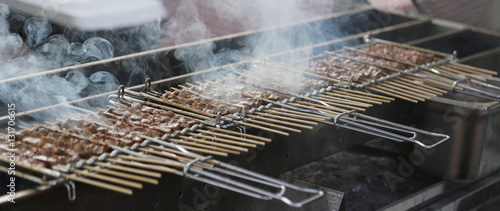 grilled meat with a lot of smoke in a street food stall photo