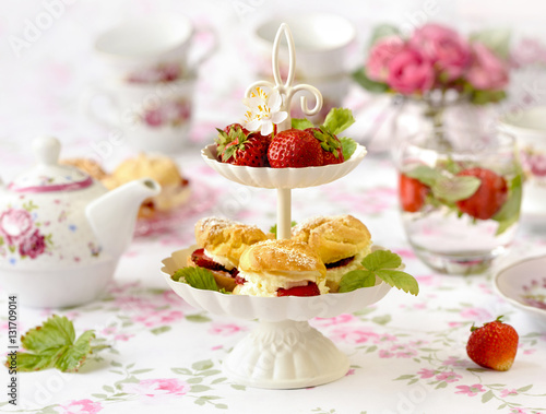 Profiterole or cream puffs cakes filled with whipped cream, strawberries in plateau