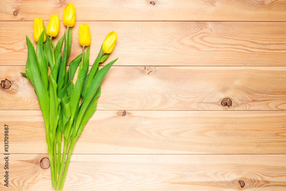 Naklejka premium wood background and a bouquet of yellow tulips top view