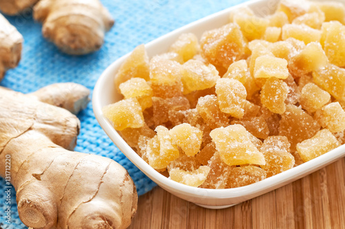 Candied ginger in white bowl on wooden table