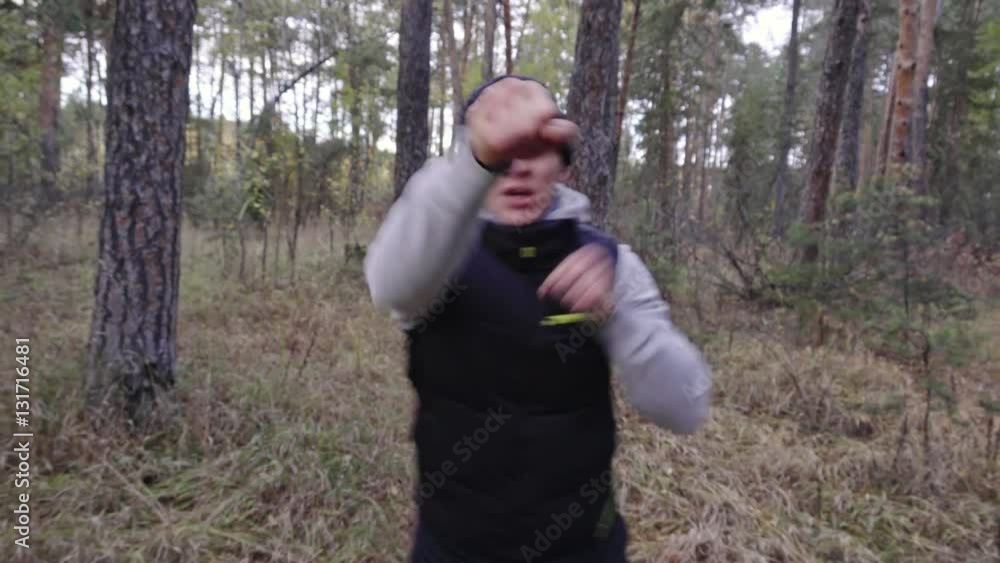 Dolly shot of young man walking towards camera in forest area and exercising with boxing tennis ball hat Dolly shot of young man walking towards camera in forest area and exercising with boxing tennis ball hat