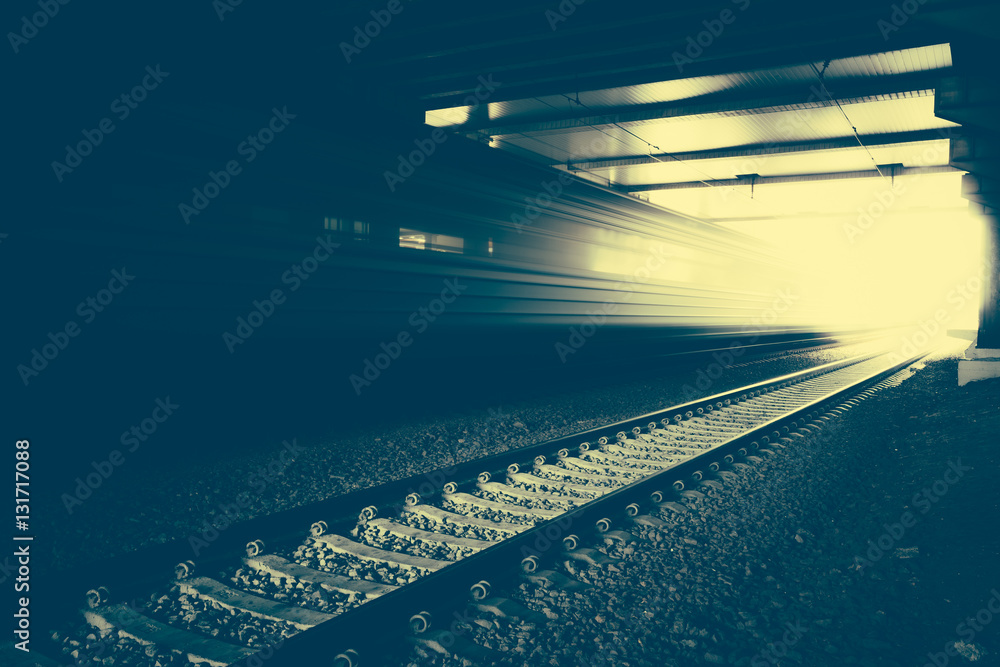 Fototapeta premium High speed passenger train on tracks moving out of tunnel with motion blur effect. Modern railway station.