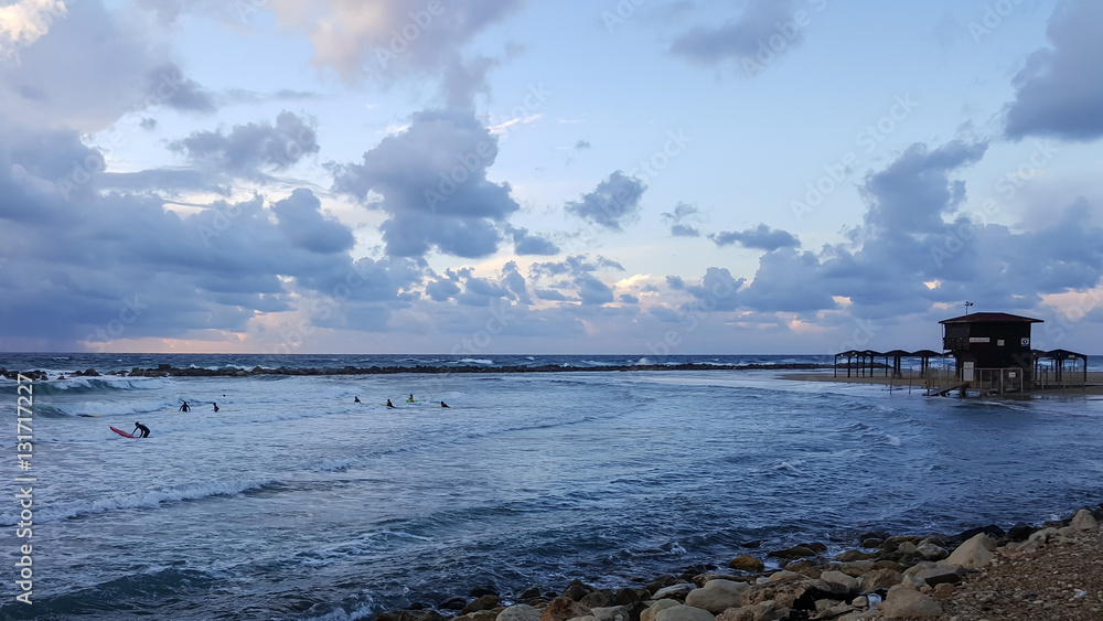 Surfers silhouetted with colourful sky and sea background