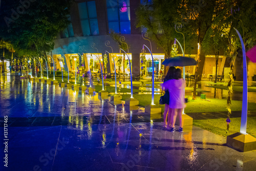 Canvas Print Women bracing under the rain at night in Singapore street