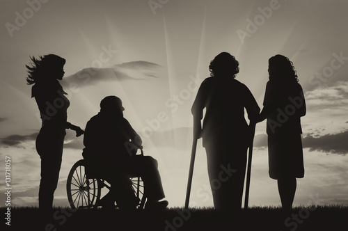 Man in wheelchair and woman on crutches with nerses photo