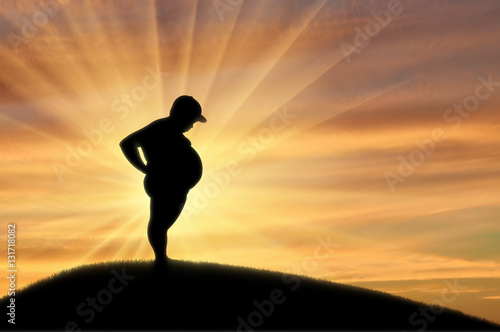 Fat child stands on hill on background of sunset