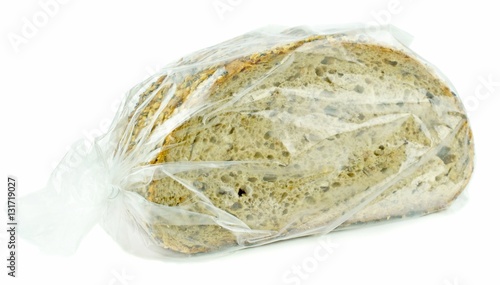 Sliced brown bread in a plastic freezer bag on a white background