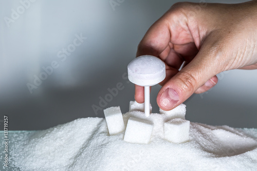 Fotografie hand picking up dextrose lollipop from heaps of refined sugar