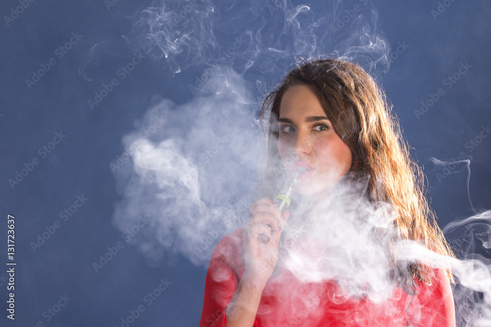 Woman Smoking an electronic Cigarette on blue Background..
