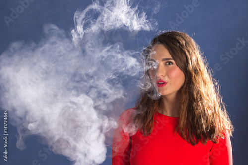Woman Smoking an electronic Cigarette on blue Background..