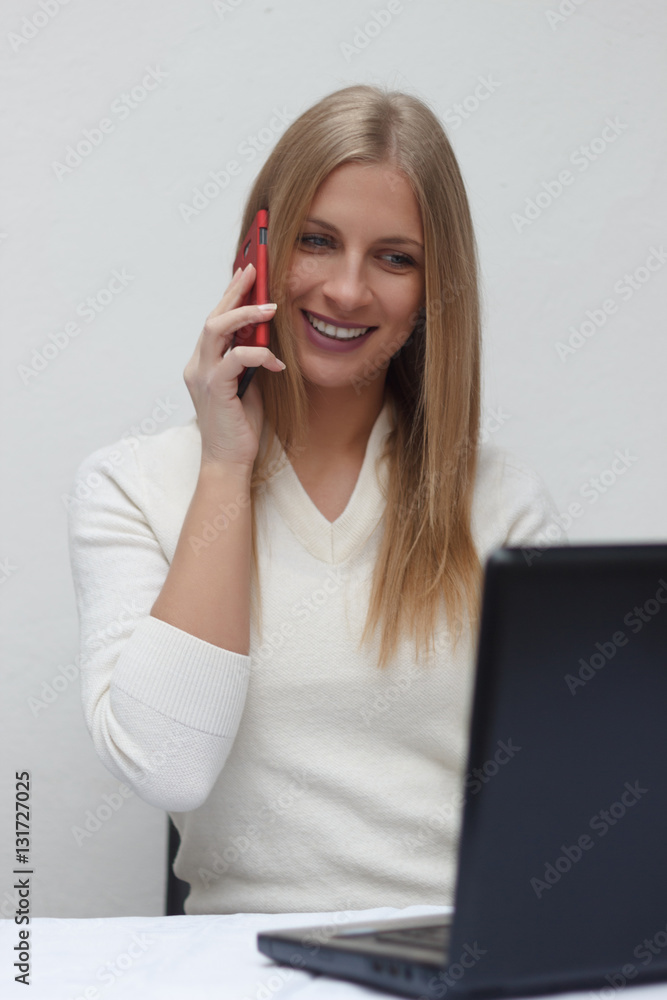 Happy smart businesswoman on the phone while using laptop in off Happy smart businesswoman on the phone while using laptop in off