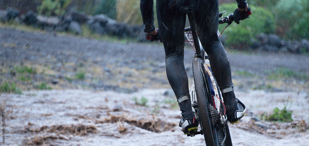 Obraz premium Mountain bikers driving in rain upstream creek