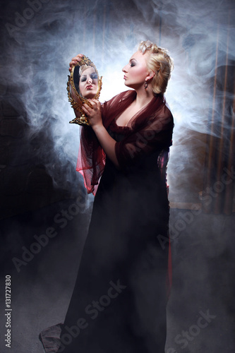 Fotografía angry blonde woman with mirror on the dark smoke background