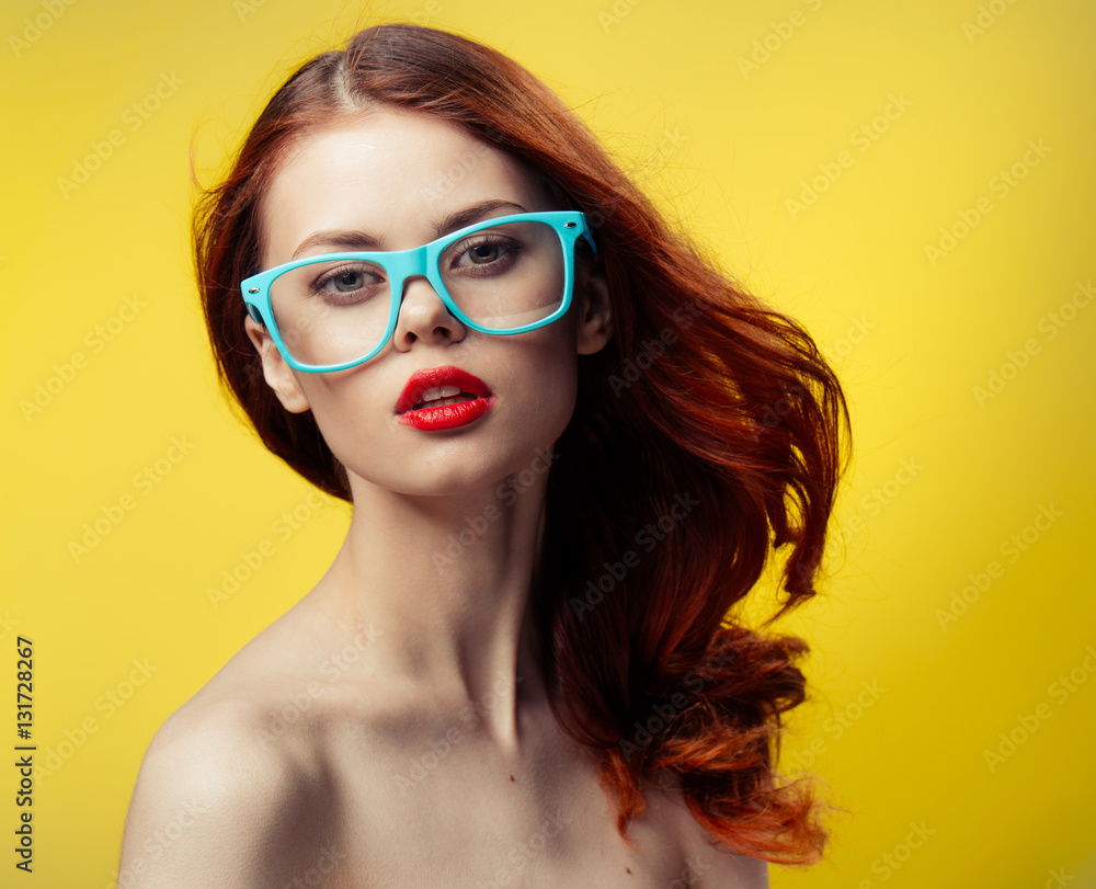 red-haired woman in glasses with a blue rim on a yellow background