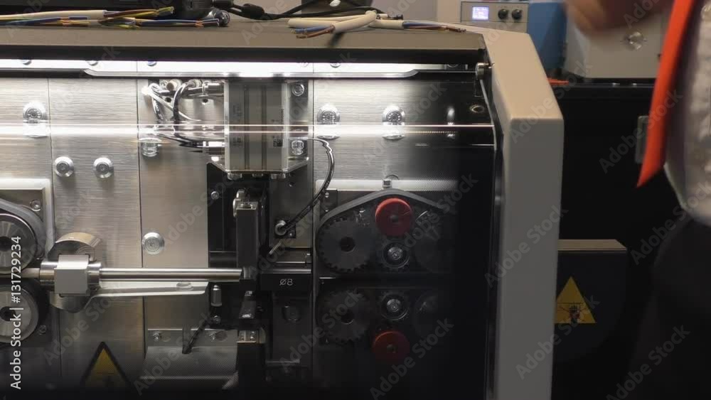 Man wearing a tie is operating wire stripping cutting automated machine Man wearing a tie is operating wire stripping cutting automated machine