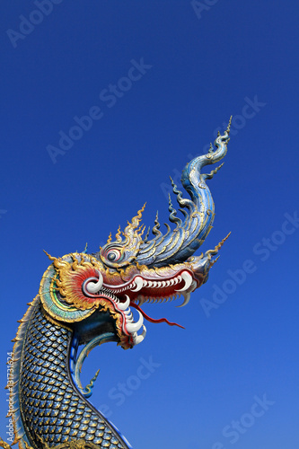 The blue head of naka or serpent statue opening mouth with blue sky background at  Wat Rong Sua Ten at Chiang Rai  Thailand - Buddhist Temple 