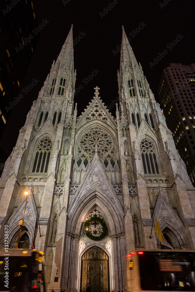 Night view of the facade of St. Patrick's Cathedral between the traffic of 5th Avenue in New York City.