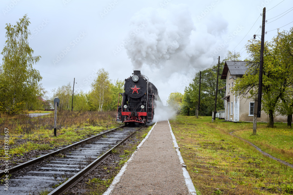 Obraz premium Steam train locomotive stopped at the small unfrequented railway station