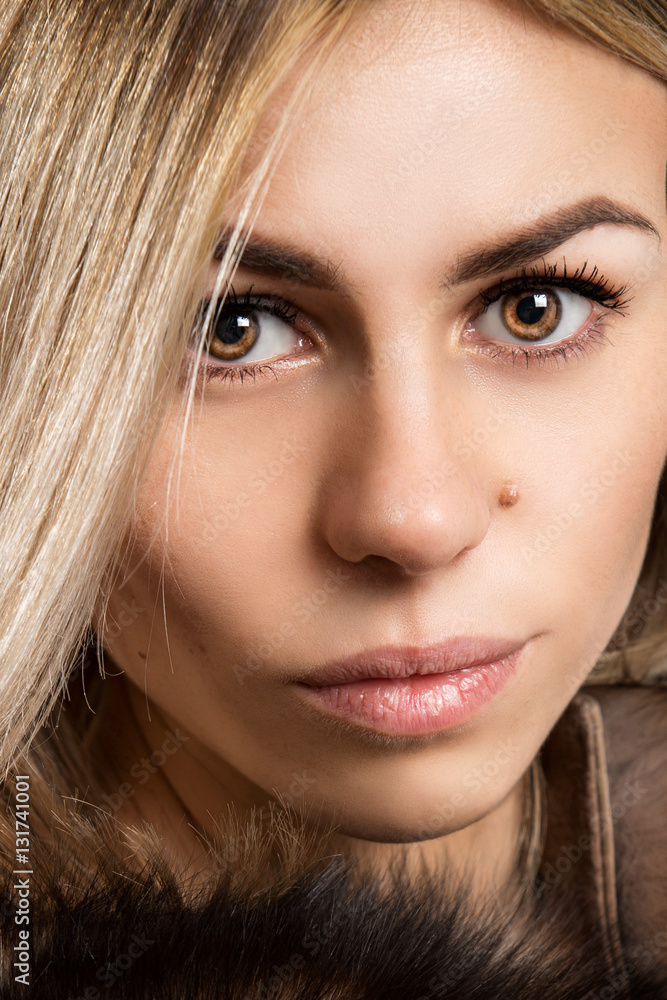 Obraz premium Portrait of a beautiful young woman dressed in a fur coat on a white background