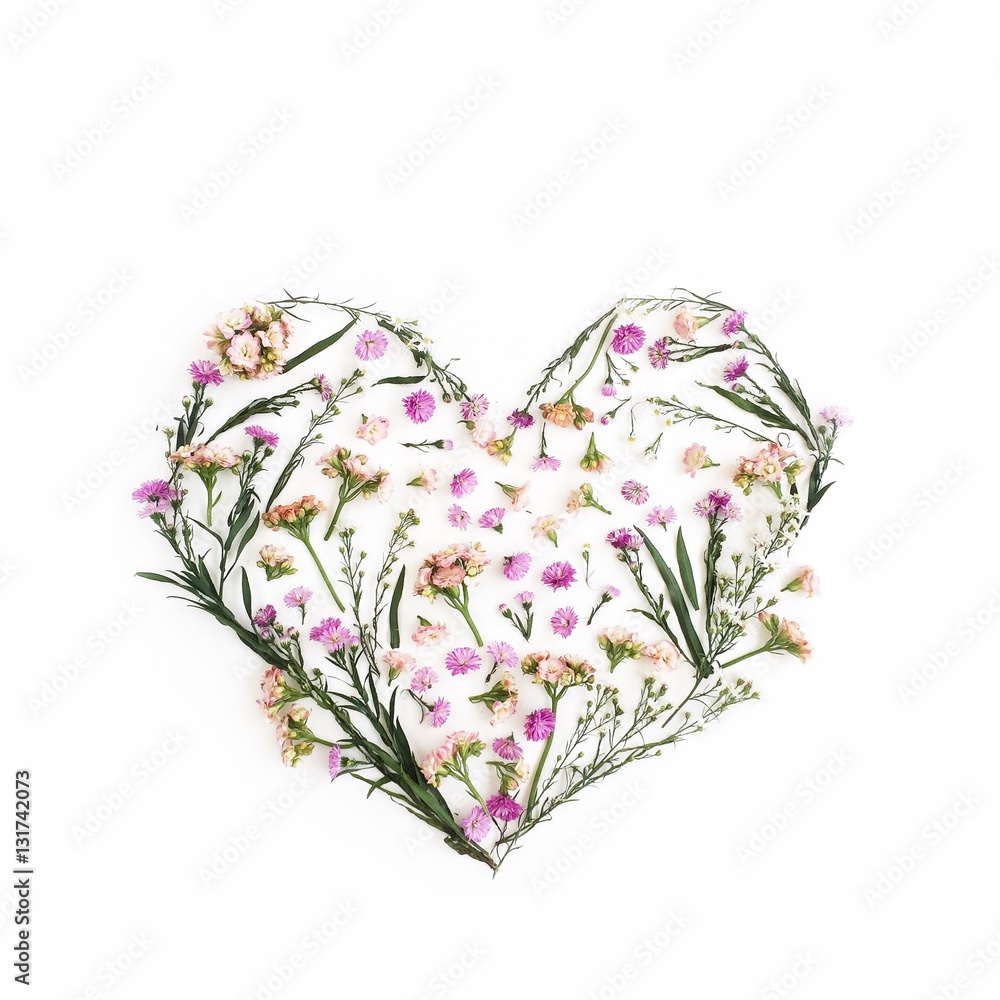 Heart symbol made of pink wildflowers. Flat lay, top view. Valentine's background.