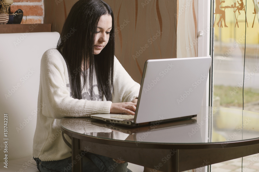 Charming beautiful young woman using laptop computer. Female working on laptop at modern office Charming beautiful young woman using laptop computer. Female working on laptop at modern office