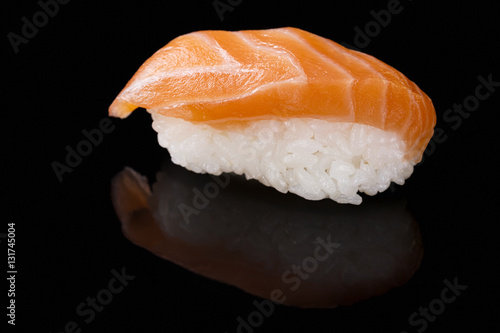 Close-up of Sake sushi with salmon on a black background with reflection.