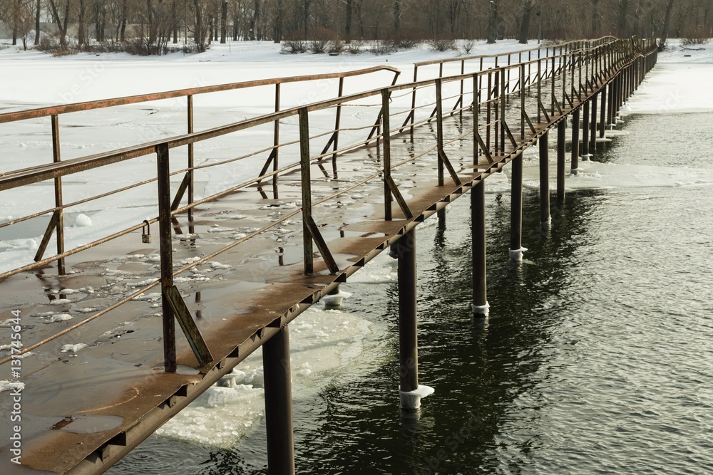 Frozen old pier at river side in winter time. Stock image.