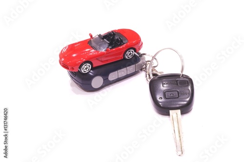 Red toy car and black car keys on white background