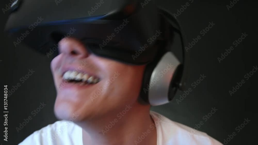 Laughing young man wearing VR Headset experiencing virtual reality. Captured with Blackmagic Production Camera 4K with RAW settings. Laughing young man wearing VR Headset experiencing virtual reality. Captured with Blackmagic Production Camera 4K with RAW settings.