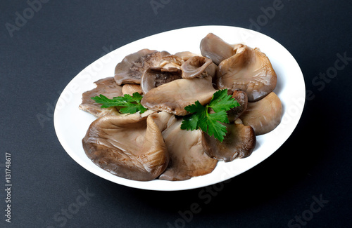 Marinated oyster mushrooms with parsley leaf on a white plate