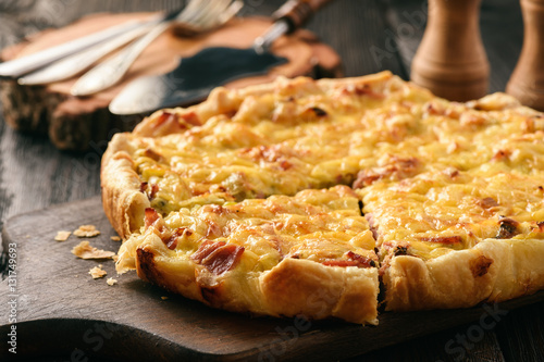 Fotografía Homemade quiche with leek, ham and cheese on wooden background.