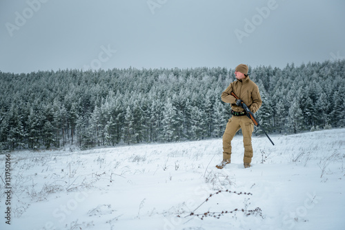 Hunter man dressed in camouflage clothing standing in the winter