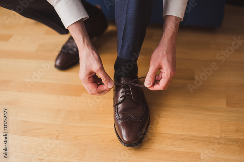 Fashion for men. Close-up of a man tie the shoelaces of his brown leather shoes