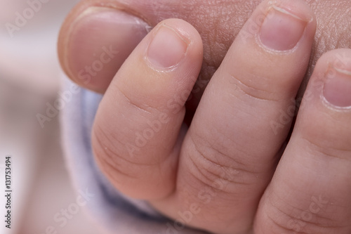 Tiny cute baby hand holding big finger close up