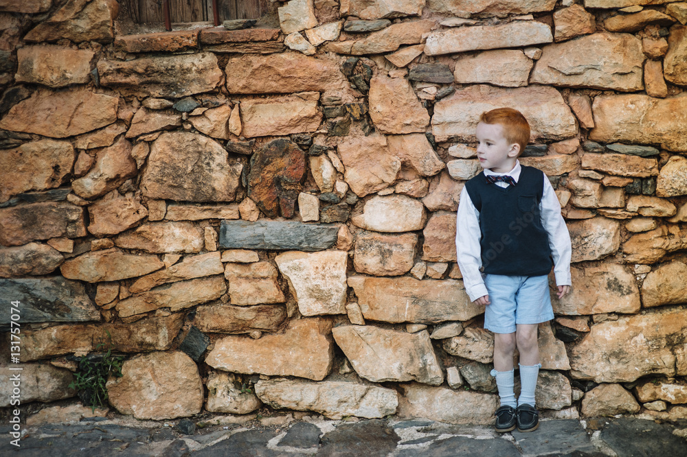 Boy with red hair standing on stone wall Boy with red hair standing on stone wall