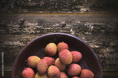 Sweet lychee fruit in a bowl on a background of old wood