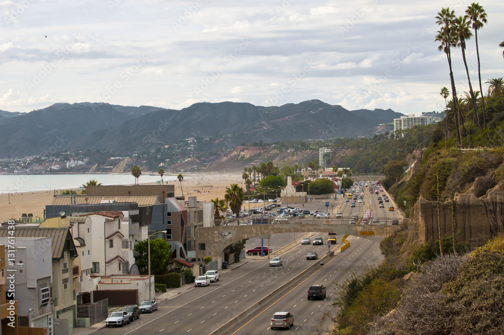 View over the car's traffic of the six lane highway 1 in Santa Monica, Los Angeles, CA, and the beach and villas on the side.