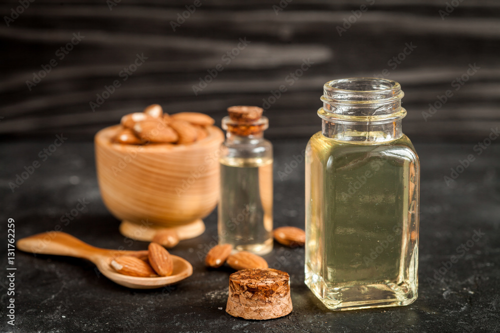 cosmetic almond oil in glass bottle on dark wooden background cosmetic almond oil in glass bottle on dark wooden background