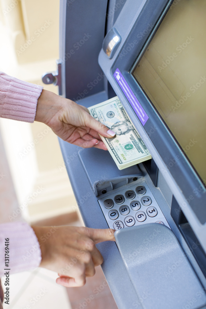Woman hand withdrawing money from outdoor bank ATM Woman hand withdrawing money from outdoor bank ATM