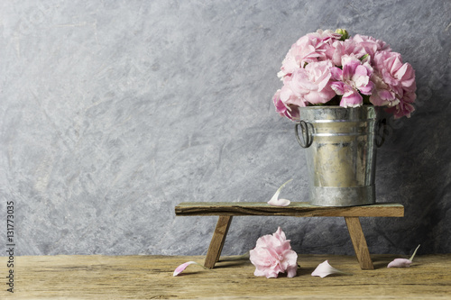 Pink carnation flowers in zinc bucket on old wood