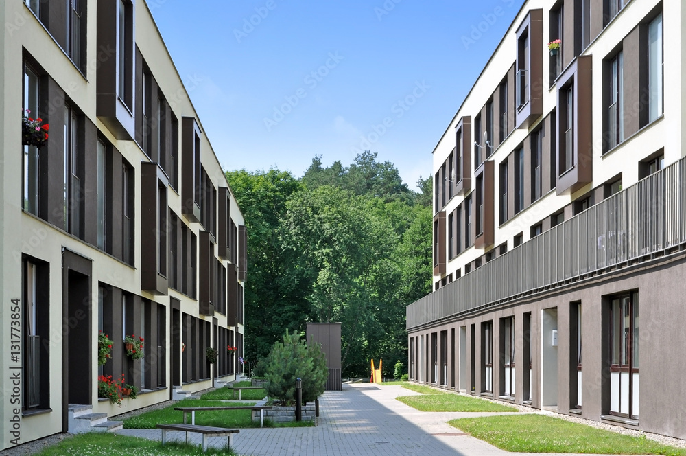 Street of a residential district with modern apartment buildings and trees in perspective.