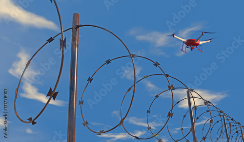 3D illustration of a UAV drone patrolling along barbed wire. Fictitious drone, motion blur for dramatic effect.