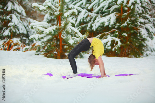 beautiful woman doing yoga outdoors in the snow photo