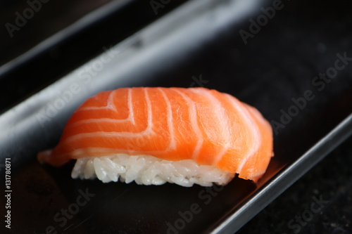 One salmon nigiri on black plate