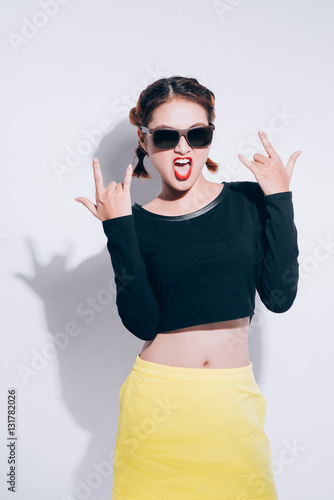 Young asian girl doing emotion. Dressed in a black shirt and yellow skirt  glasses and bright lips trendy clothes. Warm color. White background  not isolated